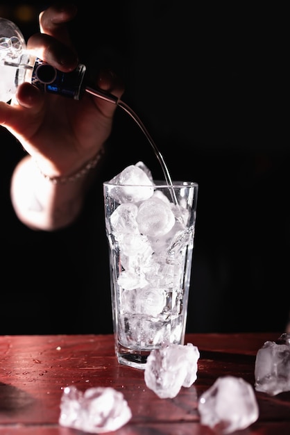 Bartender39s의 손이 얼음과 함께 잔에 알코올을 붓고 칵테일을 준비합니다. 바텐더는 손님을 위해 음료를 준비합니다. 나이트 라이프 클럽 생활 훌륭한 칵테일 서빙 놀라운 칵테일