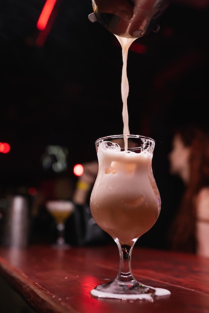 The bartender39s hand pours a milkshake closeup a glass with a
long stem the bartender prepares drinks for guests night life club
life great serving of cocktails amazing cocktails