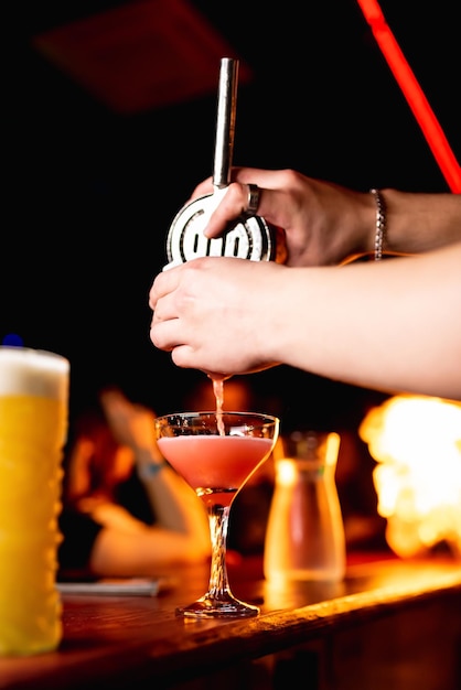 Bartender39s hands pour juice into a cocktail glass filled with an alcoholic drink in a restaurant pub Alcoholic soft drink in a nightclub