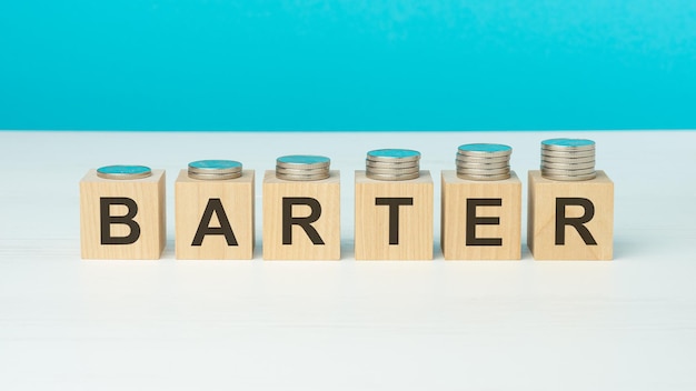 BARTER text on wooden blocks with coins on blue background
