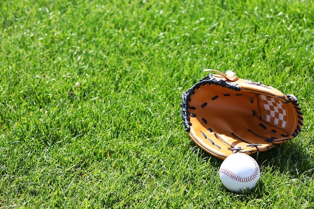 Baseball ball and glove on green field