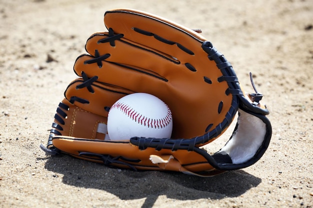 Photo baseball ball and glove on sand