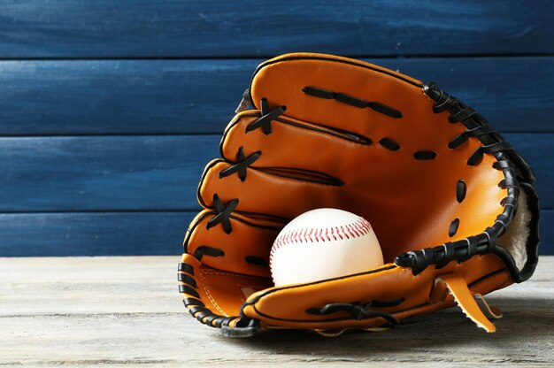 Foto palla da baseball in guanto su sfondo di legno