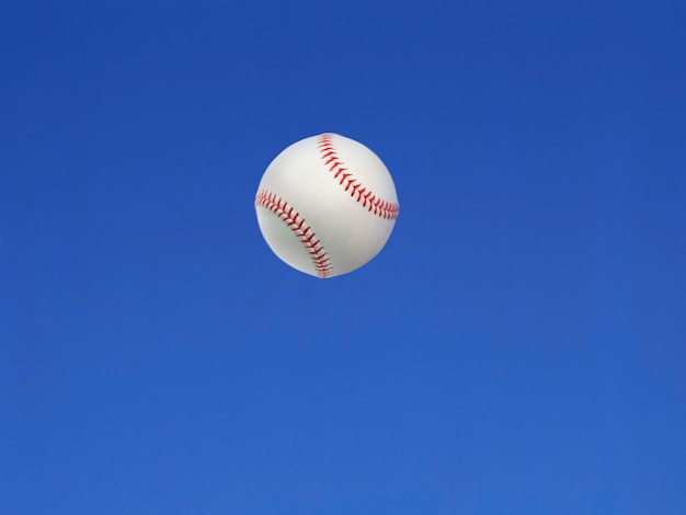 Baseball ball shot in the air with blue sky background