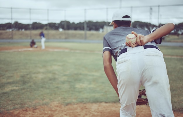 Baseball baseball player and ball on back on baseball field ready to pitch in competition game or match Fitness sports and pitcher preparing to throw for training exercise or workout outdoors