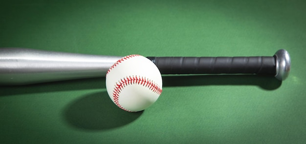 Baseball bat and baseball on the green background