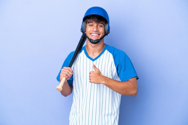 Baseball caucasian man player with helmet and bat isolated on blue background giving a thumbs up gesture