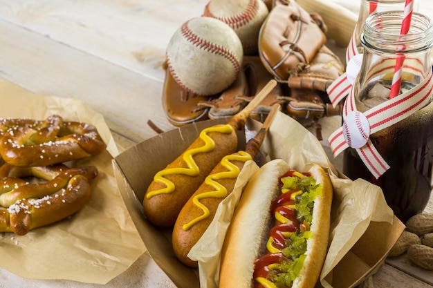 Еда для бейсбольной вечеринки с шариками и перчаткой на деревянном столе.