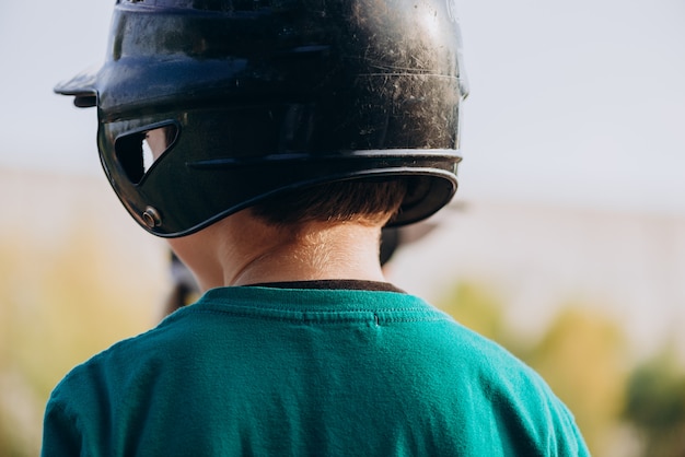 Baseball player in a helmet with his head turned to the camera, rear view