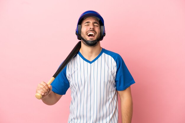 Baseball player with helmet and bat isolated on pink background laughing