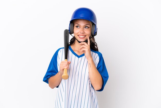 Baseball Russian girl player with helmet and bat isolated on white background thinking an idea while looking up