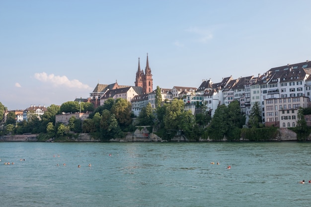 Basel, Zwitserland - 23 juni 2017: Uitzicht op de stad Basel en de rivier de Rijn, Zwitserland, Europa. Mensen zwemmen in water. Zomerlandschap, zonneschijn, blauwe lucht en zonnige dag