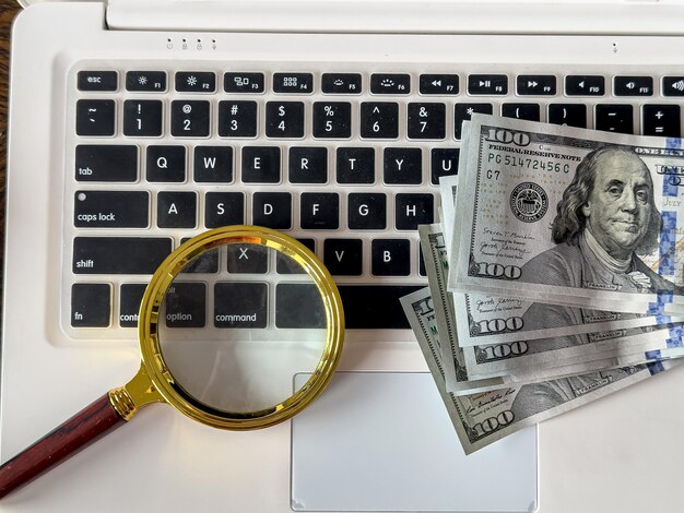 Basic Budgeting Tips with magnifying glass on laptop with us dollar money