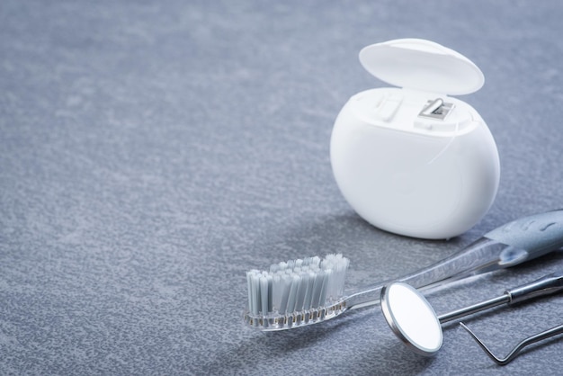 Basic dental tools floss and brush on grey surface