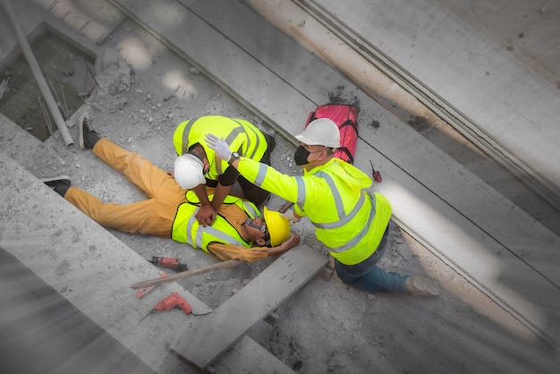 Primo soccorso di base e rcp per incidenti di emergenza nei cantieri. operaio edile è stato ferito in una caduta dall'alto in cantiere. il team di sicurezza e gli ingegneri aiutano a eseguire il primo soccorso