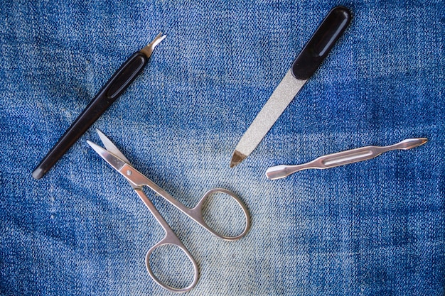Basic set of manicure tools on jeans background. Nail and cuticle scissors, cuticle trimmer, nail file