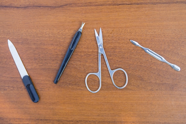 Basic set of manicure tools on wooden background. Nail and cuticle scissors, cuticle trimmer, nail file