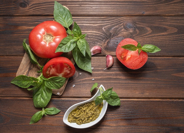 Pesto di basilico basilico fresco lascia pomodori e aglio su fondo in legno ingredienti per cucinare