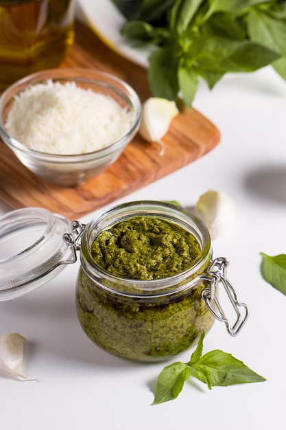 Basil pesto sauce in a jar. Ingredients for cooking, cheese, parmesan, garlic, olive oil.