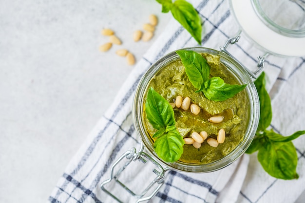 Basil pesto with nuts in a glass jar, top view.