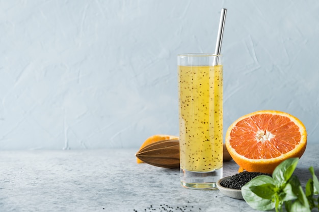 Basil seed drink with orange juice in glass on blue. Close up.