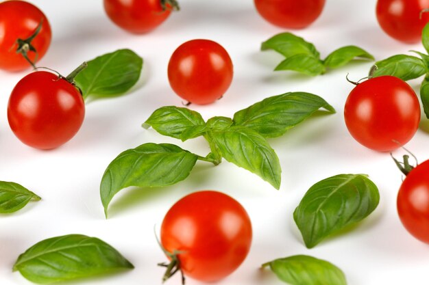 Foto basilico e ciliegia pomodorini rossi maturi e basilico su fondo bianco