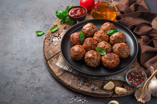 Basilicum gehaktballen, tomatensaus, kruiden en knoflook op een houten bord. Vleesschotel. Zijaanzicht, horizontaal.