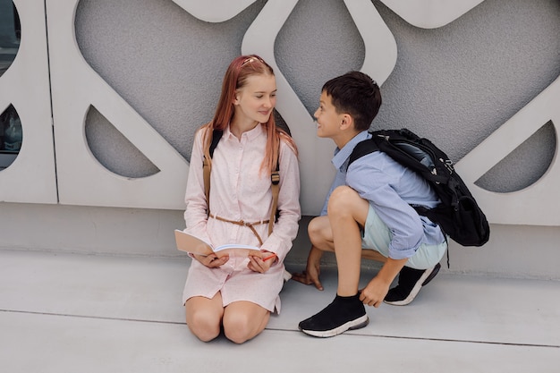 Basis secundair onderwijs, school, het concept van vriendschap - twee studentenjongen en tienermeisje met rugzakken zitten na school te praten