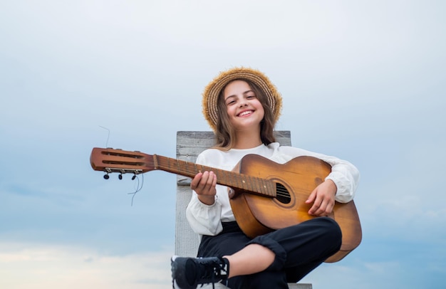 Basisakkoorden die het gitaarspel spelen op een snaarinstrument met een feestje gelukkig kind met akoestische gitaarmuziekconcept zingende liedjes getalenteerde meisjesmuzikant lifestyle en mensenconcept