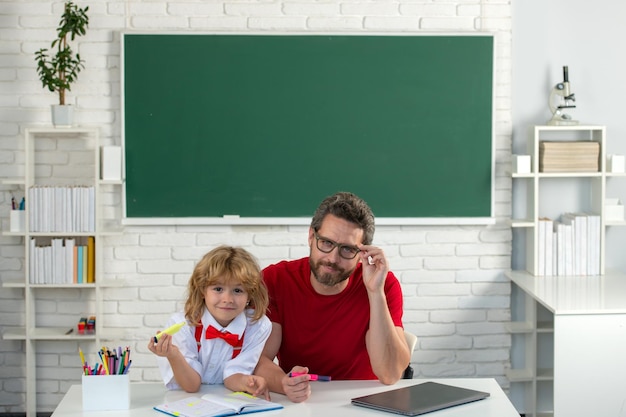 Basisschool jongen in de klas op les Leraar legt uit aan leerling Vader leraar helpt een zoon jongen in schoollessen