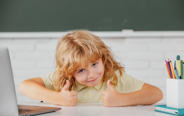 Basisschool jongen met duimen omhoog werken in de computerklas