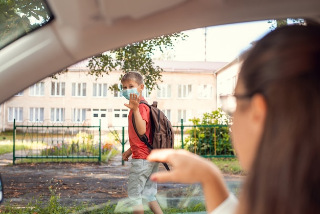 Foto basisschoolleerling die 's ochtends naar school gaat met een beschermend masker