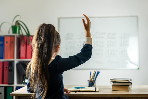 Basisschoolleerling steekt haar hand op omdat ze klaar is om de vraag van de leraar te beantwoorden