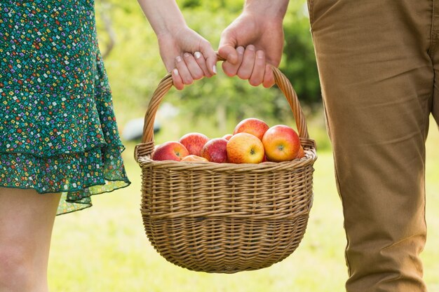 若いカップルが運ぶリンゴのバスケット