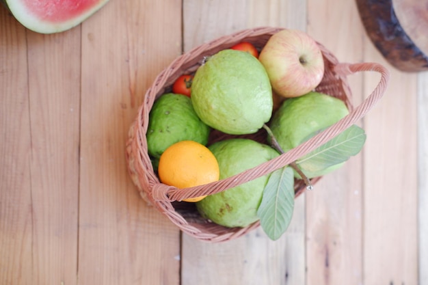 Basket of apples oranges guava and watermelon on a wooden table stock photo
