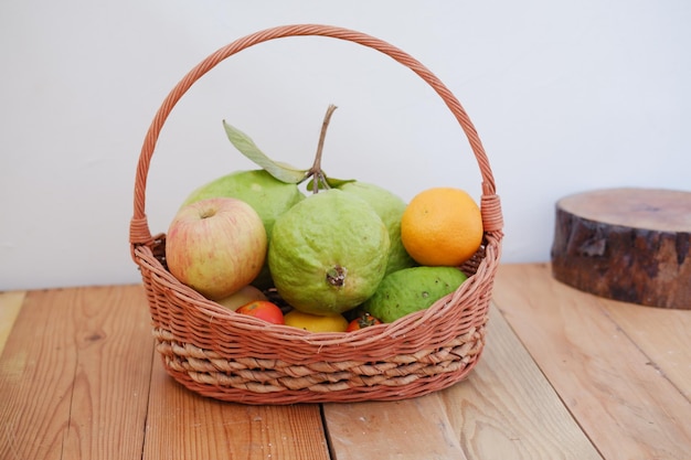 Basket of apples oranges and guava on a wooden table stock photo