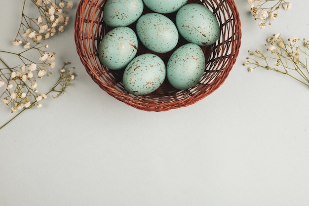 A basket of blue eggs with flowers on a white background