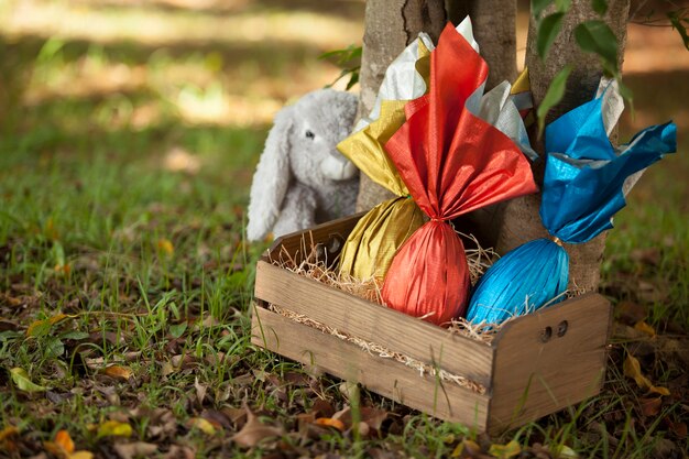 Basket of brazilian Easters eggs under a tree, with a bunny in the wall