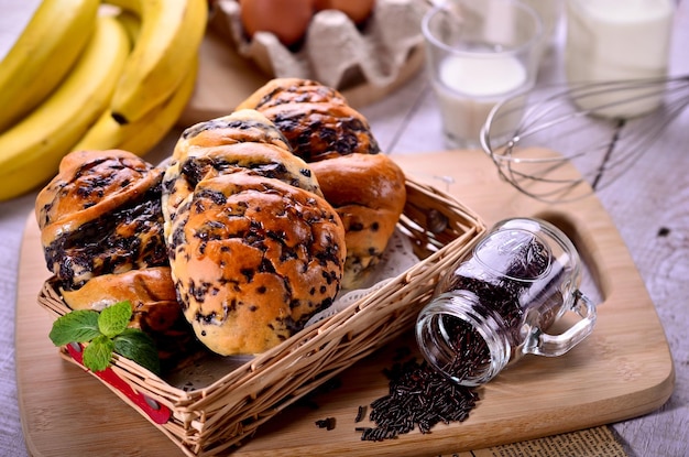 A basket of bread with a jar of black chia seeds next to it.