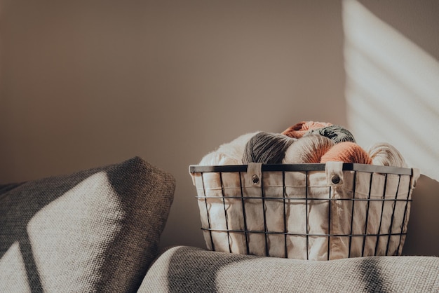 Basket of earth coloured skeins of yarn inside an apartment sunlight from the window on it