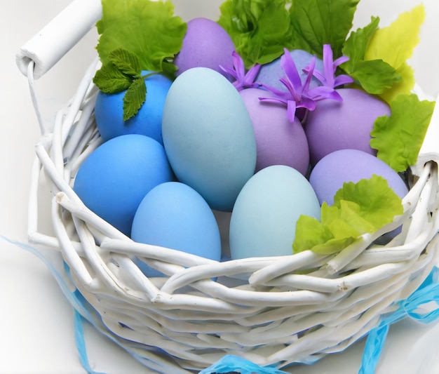 a basket of easter eggs with a purple flower in the middle