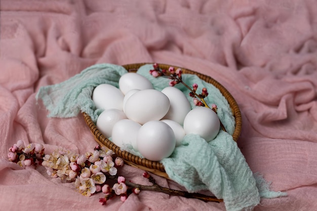 A basket of eggs with flowers on a pink blanket