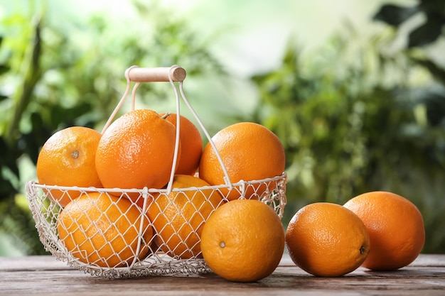 Basket and fresh oranges on wooden table Space for text