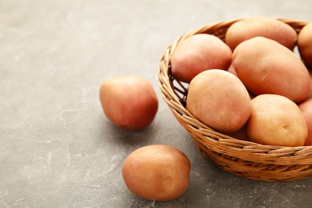 Cesto di fresche gustose patate novelle su sfondo grigio. vista dall'alto