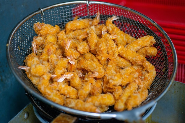 A basket of fried shrimp is shown with a red background.