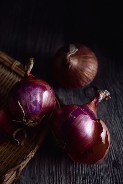 A basket of onions sits on a wooden table.