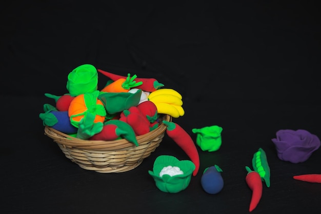 Basket of plasticine vegetables and fruits on a black background