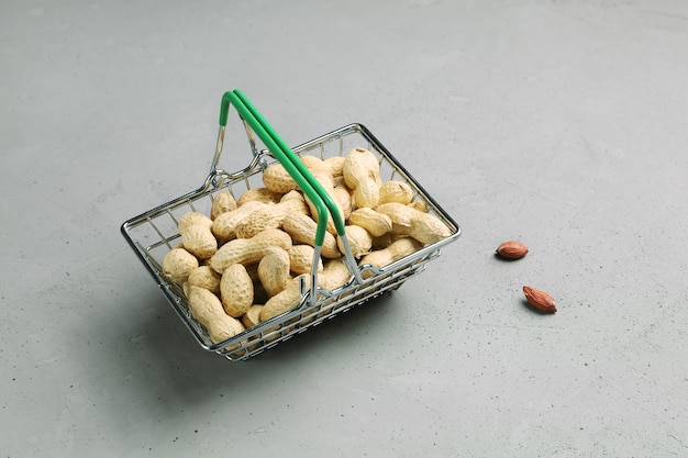 Basket for products with peanuts in shell on gray background