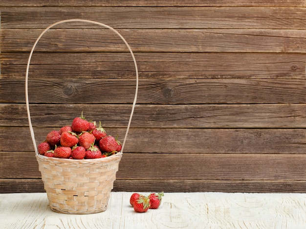 Photo basket of ripe strawberries on a wooden background. space for text