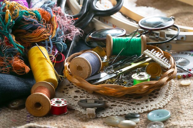 Foto un cesto di accessori per cucire si trova su un tavolo con una macchina da cucire e altri accessori per cucire.